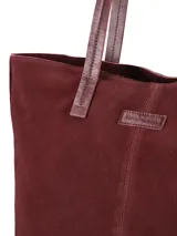 Cartera tipo tote bag de gamuza color bordó, con doble asa larga para el hombro y costura vertical central con detalle de etiqueta grabada.