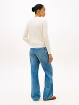 Sweater de punto trenzado color blanco de Tommy Hilfiger, con cuello en V, mangas largas y detalles acanalados en puños y dobladillo. Presenta el logo de la marca bordado en el pecho.