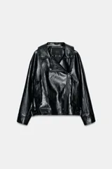 Chaqueta de estilo biker confeccionada en tejido efecto piel con acabado brillante. Presenta cuello con solapas, cierre frontal con cremallera y botones, bolsillos delanteros y bajo ajustable con trabillas y hebilla metálica.