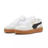 Championes Puma modelo Palermo, con diseño retro de perfil bajo. Presentan una combinación de cuero blanco y gamuza en tonos claros, con detalles en rosa pálido y una suela de goma color caramelo. Incluyen el logo de la marca en dorado en el lateral.