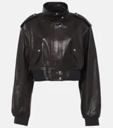 Campera bomber corta de cuero sintético negro, con cuello alto, cierre frontal y detalles de botones metálicos plateados en hombros y bolsillos frontales.