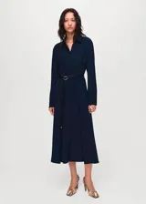 Vestido midi de corte evasé en color azul marino, con cuello camisero, cierre frontal de botones ocultos y mangas largas con puños abotonados. Incluye un cinturón fino ajustable con hebilla metálica.