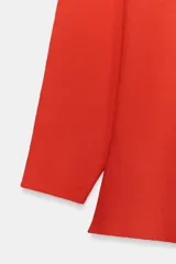 Jersey rojo de punto con escote en V pronunciado tanto en el delantero como en la espalda, mangas largas y diseño entallado en la cintura con caída acampanada.