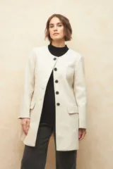 Tapado largo color crema, de paño, con cuello a la base y botones redondos veteados.