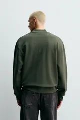 Sudadera de corte regular fit confeccionada en tejido de algodón con interior de rizo. Presenta cuello tipo rib, cierre frontal de cremallera y acabados en rib en puños y bajo.