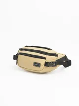 Riñonera negra de diseño funcional con múltiples compartimentos. Cuenta con dos bolsillos frontales con cierre, un bolsillo trasero oculto de seguridad y una manija superior. Incluye correa ajustable con cierre de broche y parche con logo de la marca en el frente.