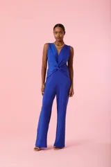 Mono largo de color azul eléctrico, sin mangas, con escote en V profundo y detalle de nudo frontal en la cintura. Presenta un corte recto y fluido en las piernas.