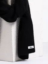 Bufanda de tejido de punto acanalado en color negro, con etiqueta de marca en uno de sus extremos.