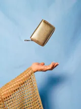 Billetera compacta de cuero natural con acabado metalizado dorado y cierre perimetral. Cuenta con compartimentos internos para tarjetas, billetes y un bolsillo para monedas.