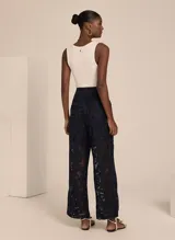 Pantalón de encaje negro con corte recto, tiro alto, cierre frontal con cremallera, dos bolsillos y forro incorporado.