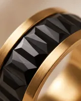 Anillo de acero con baño dorado y diseño ancho, con incrustaciones de circonias negras talladas en forma de baguette en todo su contorno.