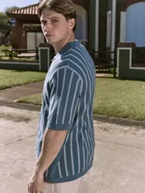 Polo de punto azul con rayas verticales blancas, cuello tipo camisa, cierre con botones y mangas cortas.