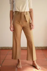 Pantalón de vestir color camel, de corte ancho, con bolsillos laterales y cinturón de la misma tela.
