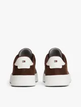 Zapatillas de corte bajo Tommy Hilfiger confeccionadas en una combinación de piel nobuk y piel lisa en color marrón. Presentan suela de goma blanca, detalle de ventilación lateral, logo de la marca en la lengüeta, lateral y talón, y cierre mediante cordones.