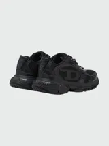 Zapatillas deportivas Diesel modelo S-Pro-V-Dense, color negro, con diseño robusto y estilo 'chunky' o 'dad shoe'. Presentan una combinación de malla transpirable y superposiciones de material sintético brillante. Los cordones son bicolores (negro y blanco).