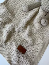 Manta tejida en hilo de algodón color beige, con diseño calado y borde tejido a punto santa clara.