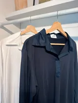 Chomba de algodón blanca con cuello camisero y cierre frontal parcial, de manga larga y calce holgado.