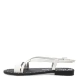 Sandalias planas Miss Carol modelo Sorel, con diseño de tiras cruzadas blancas y ajuste de hebilla en el tobillo. La plantilla es negra con detalle de tachas metálicas en el borde.