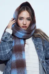 Bufanda oversized de textura suave con diseño a cuadros en tonos marrón y azul.