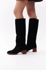 Bota de caña alta color beige, confeccionada en cuero gamuzado. Tiene taco de madera y puntera redondeada.