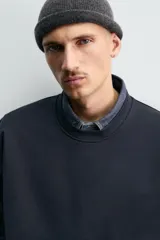 Sudadera de corte relajado confeccionada en algodón compacto con interior de rizo. Presenta cuello redondo acabado en rib, manga larga y bordes irregulares enrollados.