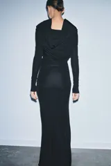 Vestido largo negro de manga larga confeccionado en mezcla de viscosa. Presenta cuello amplio multiposición y detalle de drapeado fruncido en el lateral del torso.