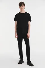 Jean de corte skinny con ajuste estrecho en la pierna, confeccionado en denim elástico color negro. Presenta tiro medio y cierre con bragueta.