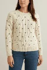 Sweater tejido en lana merino cruda con pequeños bordados en forma de corazón color marrón.