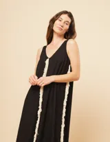 Vestido largo blanco de lino con escote en V y flecos de algodón en los bordes.