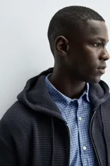 Sudadera hoodie relaxed fit color azul marino, confeccionada en tejido waffle con estructura cuadrillé. Cuenta con capucha ajustable, manga larga, bolsillos delanteros tipo canguro, acabados en rib y cierre frontal de cremallera. Presenta un efecto lavado.