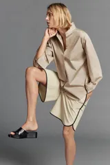 Camisa oversize color beige con mezcla de algodón, cuello smoking, manga larga con puños anchos y cierre frontal con botones ocultos por solapa.
