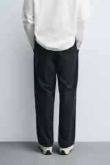 Pantalón de corte relaxed fit confeccionado en mezcla de algodón y modal. Presenta cintura con pliegues frontales, bolsillos laterales y bolsillos traseros con solapa. Cierre frontal con cremallera y botón.