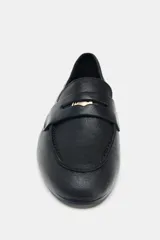 Mocasín de piel color negro con antifaz en la parte delantera y detalle de penny dorado. Tiene copete subido y punta redonda.