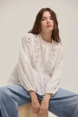Blusa de algodón color blanco con diseño romántico, cuello redondo, mangas largas abullonadas con puños elásticos y detalles de bordado inglés y encaje en el frente y hombros.
