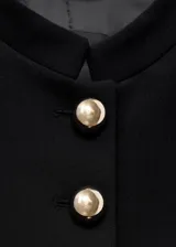 Chaqueta entallada de color negro con cuello mao y cierre frontal de botones dorados. Presenta un diseño estructurado de manga larga y forro interior.