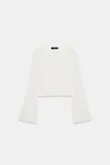 Jersey de punto pointelle color blanco, con cuello redondo y mangas largas y acampanadas.