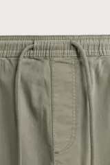 Bermuda cargo color negro de corte relaxed fit, confeccionada en tejido de algodón con elasticidad y efecto lavado. Cuenta con cintura elástica ajustable con cordón, bolsillos frontales y bolsillos laterales tipo cargo con solapa en las perneras.