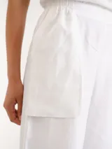 Pantalón blanco de lino con diseño de corte recto y amplio, bolsillos laterales superpuestos y cintura elástica.