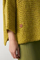 Sweater tipo poncho de tejido de punto grueso, color verde oliva, con cuello alto holgado y diseño de caída amplia.