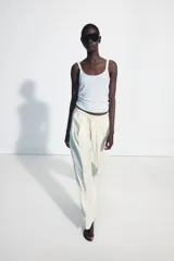 Pantalón fluido de tiro medio, color blanco, con cintura elástica ajustable con cordones, bolsillos laterales y bajo ajustable con trabilla y botón a presión.