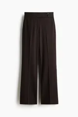 Pantalón de sarga color marrón oscuro, de tiro alto y corte bootcut. Cuenta con pretina ancha con detalle de dos botones en el lateral, pliegues marcados en el frente y bolsillos laterales.