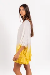 Vestido corto de algodón con diseño en degradé blanco y amarillo, escote redondo, mangas murciélago con volados y volado en el ruedo.