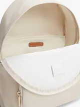 Mochila Tommy Hilfiger de nailon color beige, con diseño curvo, bolsillo frontal con cierre y detalles en cuero sintético marrón en el asa superior. Cuenta con el monograma TH metálico dorado en la parte delantera y correas ajustables.