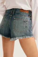 Short de denim azul con efecto desgastado, tiro medio, bolsillos clásicos y terminación de ruedo deshilachado.