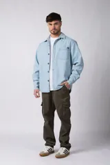 Chaqueta de denim celeste de corte relajado, con cuello clásico, cierre frontal con botones metálicos y un bolsillo aplicado en el pecho.