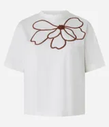 Blusa boxy de mangas cortas color blanco, confeccionada en algodón, con cuello redondo y bordado floral en el frente.