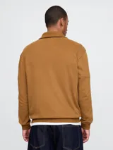 Buzo de algodón con medio cierre frontal y cuello tipo polo. Presenta el logo de la marca Gap bordado en el pecho en tonos azules.