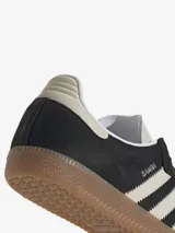 Zapatillas Adidas Samba OG, color negro con las tres tiras laterales en blanco y suela de goma marrón.