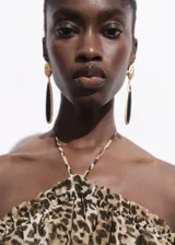 Vestido largo de cuello halter con estampado de leopardo. Presenta un diseño con cuerpo fruncido y un volante en la parte superior, confeccionado en tejido fluido con caída.