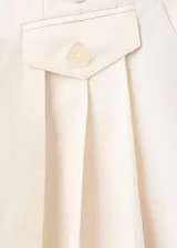 Pantalón sastrero de algodón color marfil, de tiro bajo y diseño recto de pernera ancha. Cuenta con pinzas frontales, bolsillos laterales y un pequeño bolsillo con solapa y botón en la cintura.